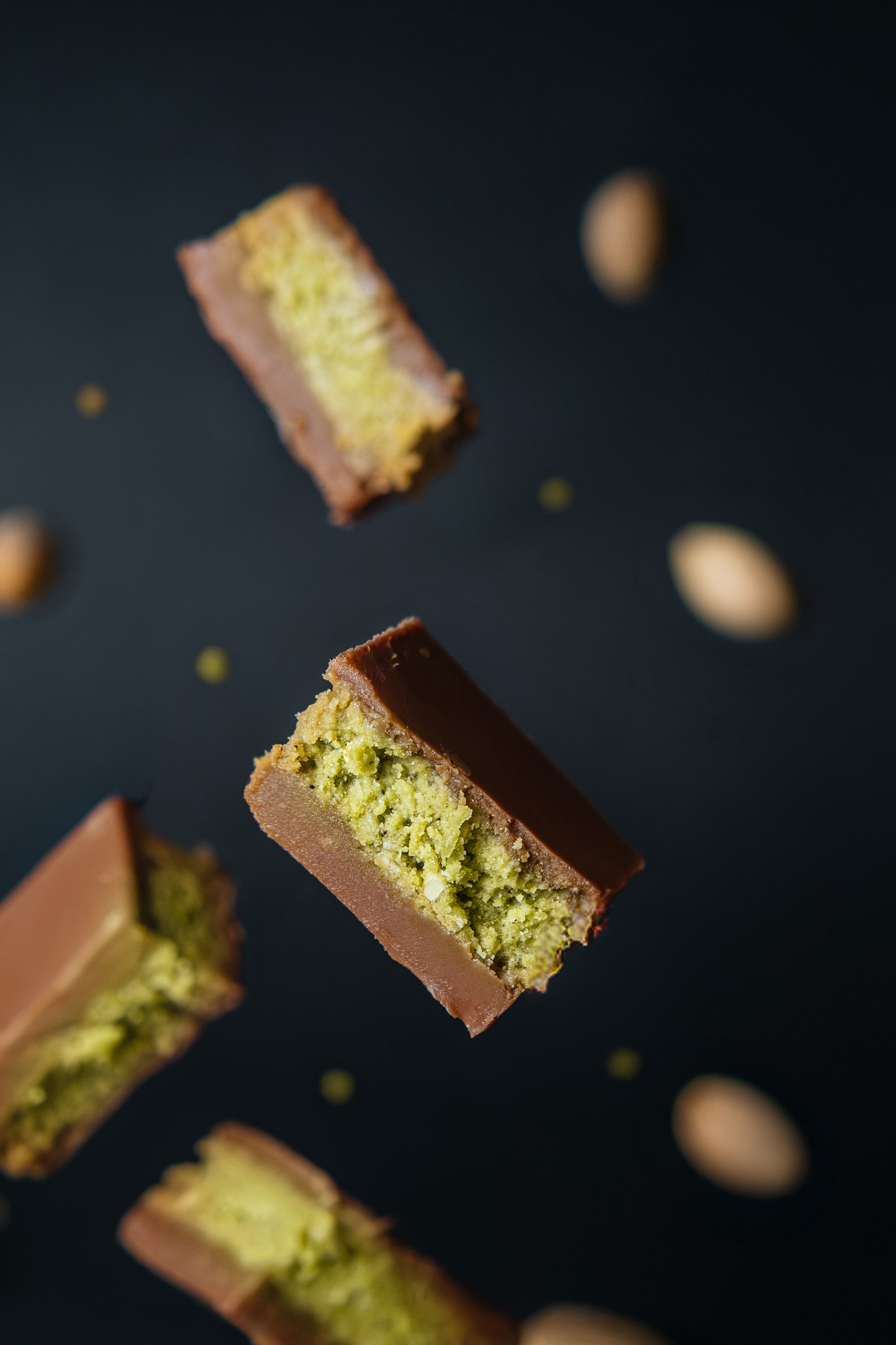 Composición de pequeños dulces de chocolate con relleno verde sobre fondo oscuro.