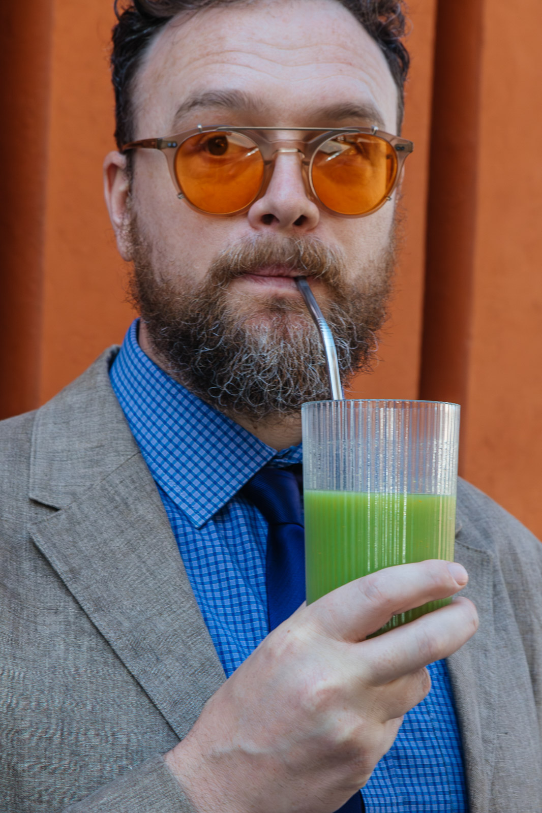 Persona con gafas de color naranja sostiene una bebida verde en Fresora.