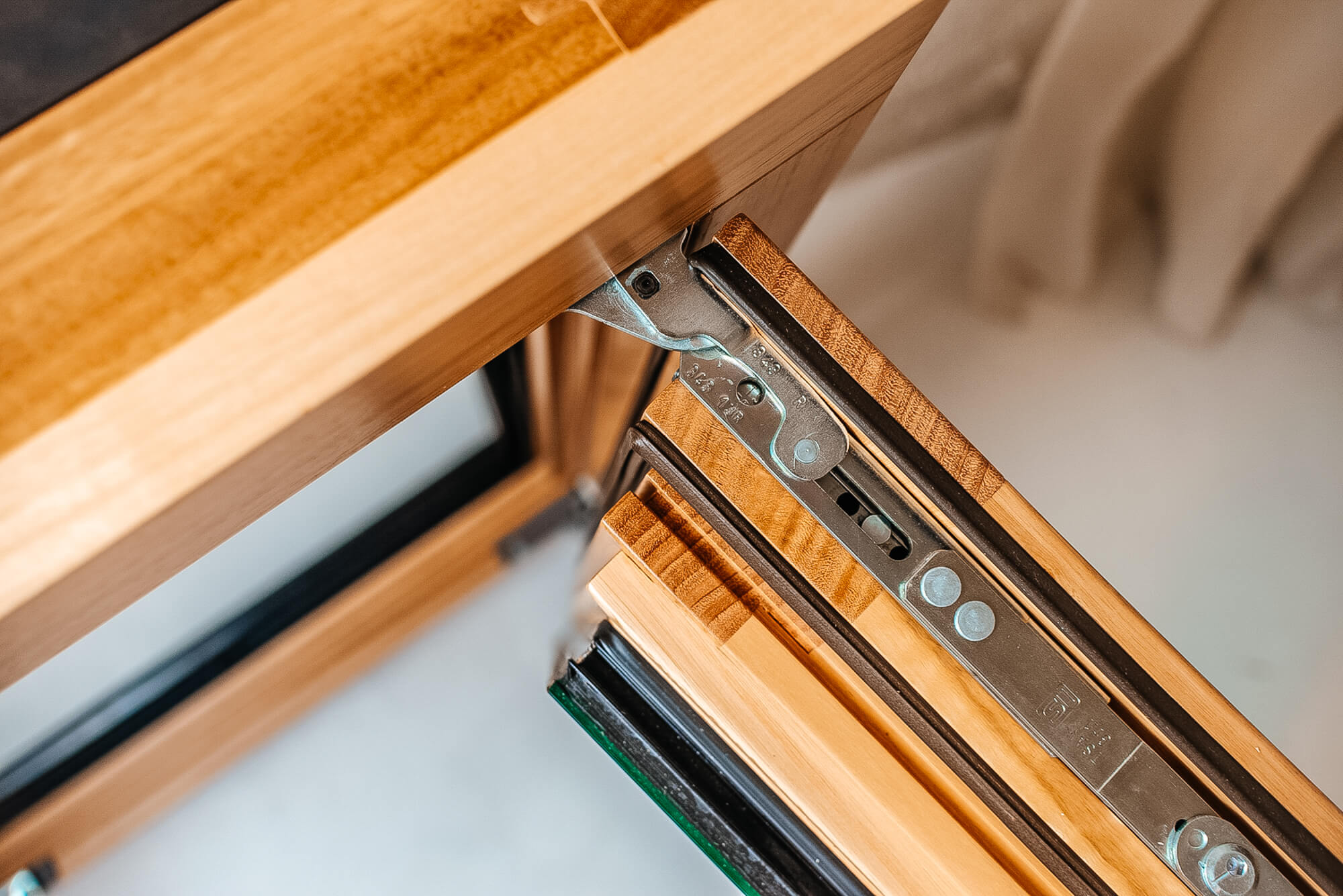 Detalle de la bisagra y el perfil de madera de una ventana abierta.