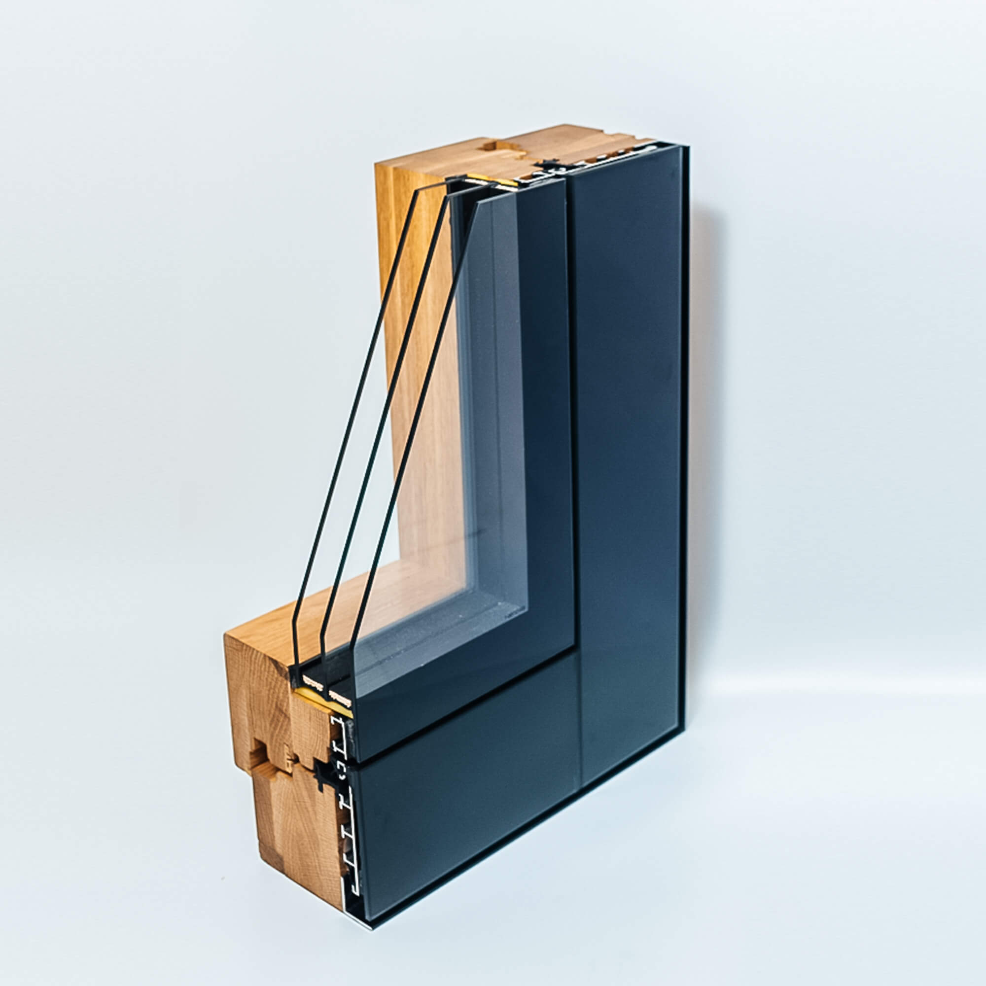 Muestra de perfil de ventana en tonos oscuros con sección de madera y vidrio.