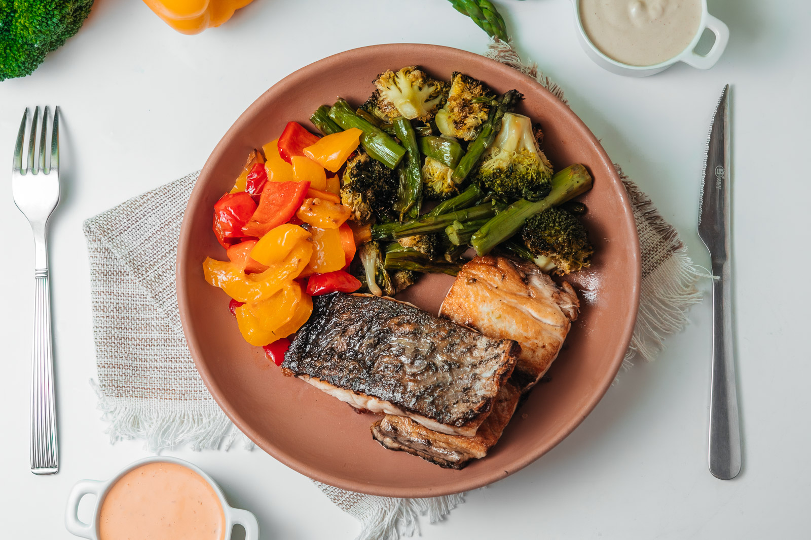 Plato de pescado con verduras y guarnición fotografiado desde arriba.