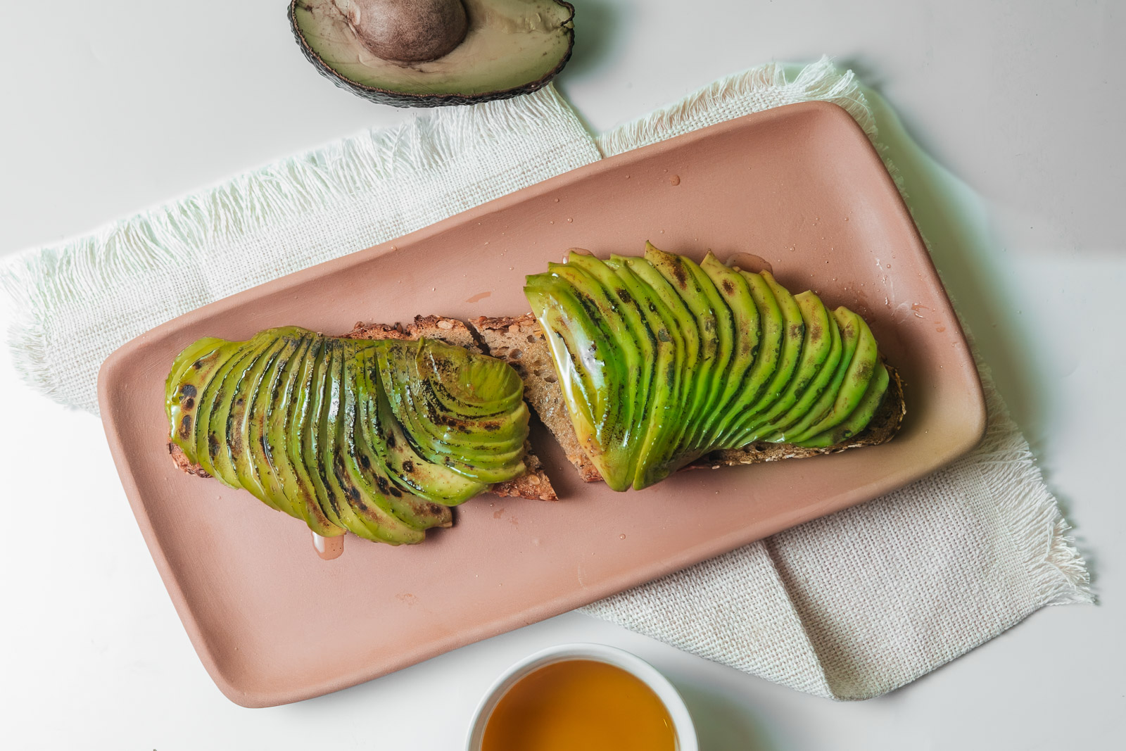 Tostadas con láminas de aguacate presentadas sobre una tabla.