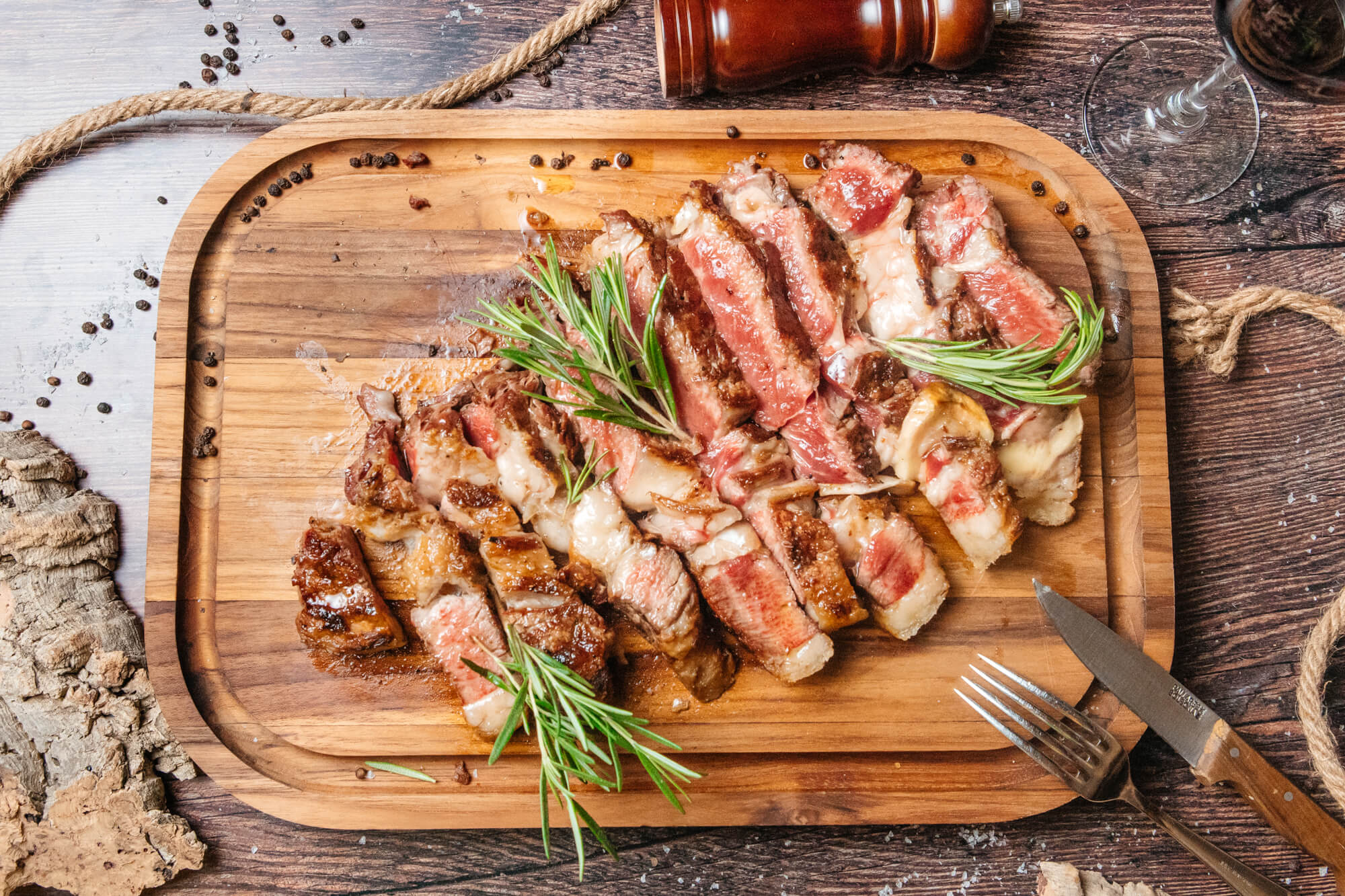 Carne a la parrilla cortada en tiras y presentada sobre una tabla de madera.