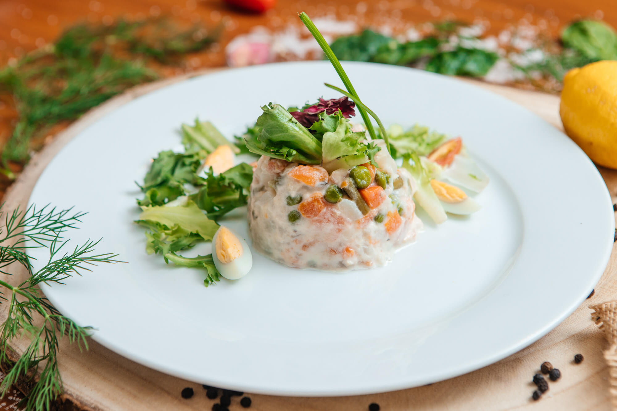 Plato de tartar con hojas verdes y guarnición sobre una mesa de restaurante.