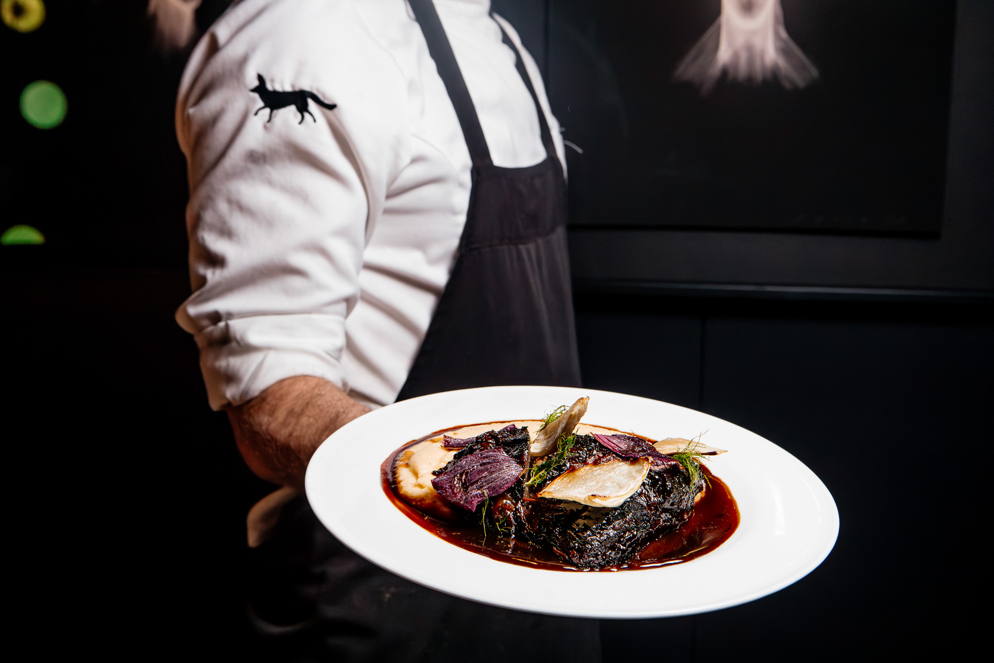 Miembro del equipo de sala presenta un plato de carne en MR PORTER.