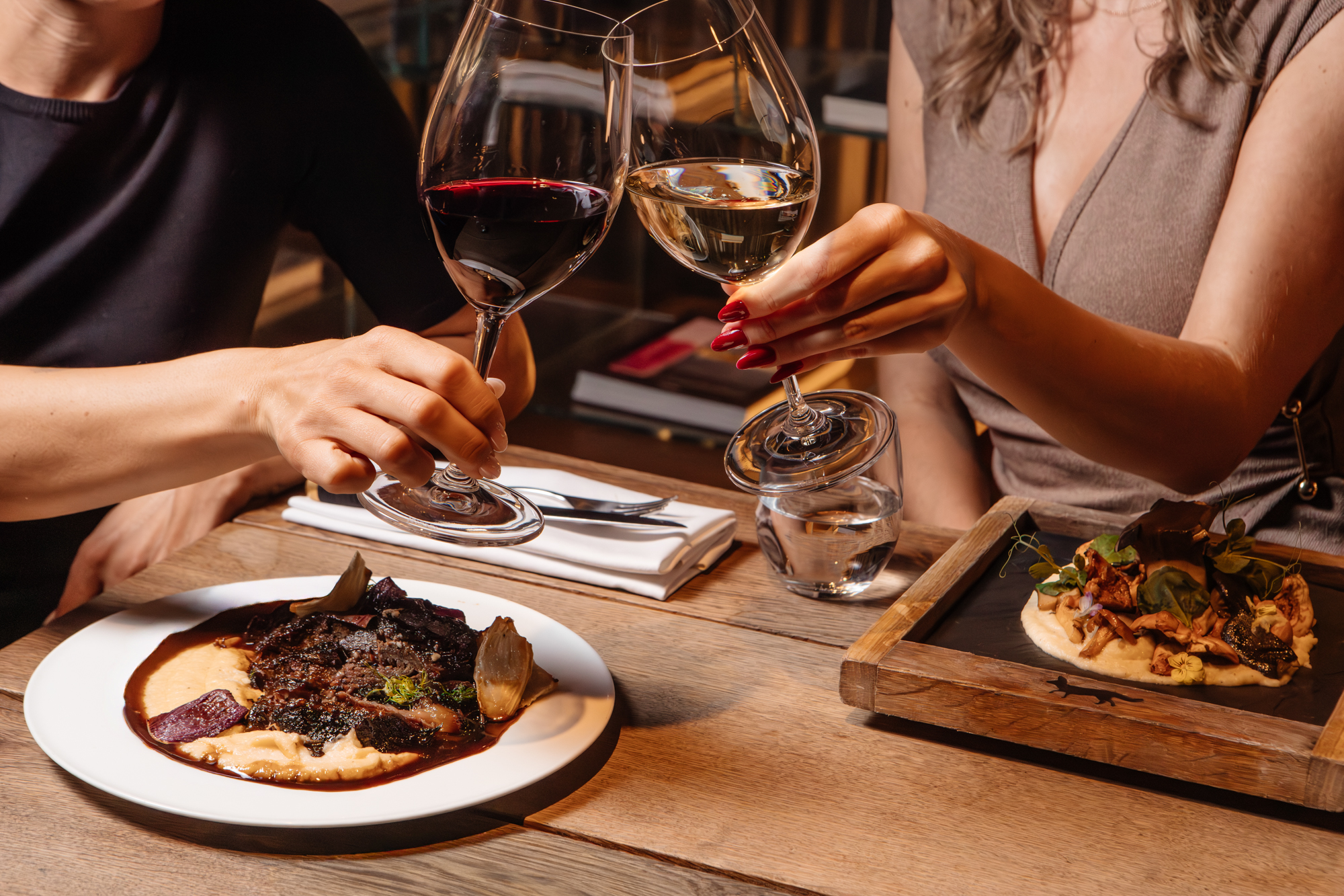 Brindis con vino junto a platos de carne en MR PORTER Barcelona.