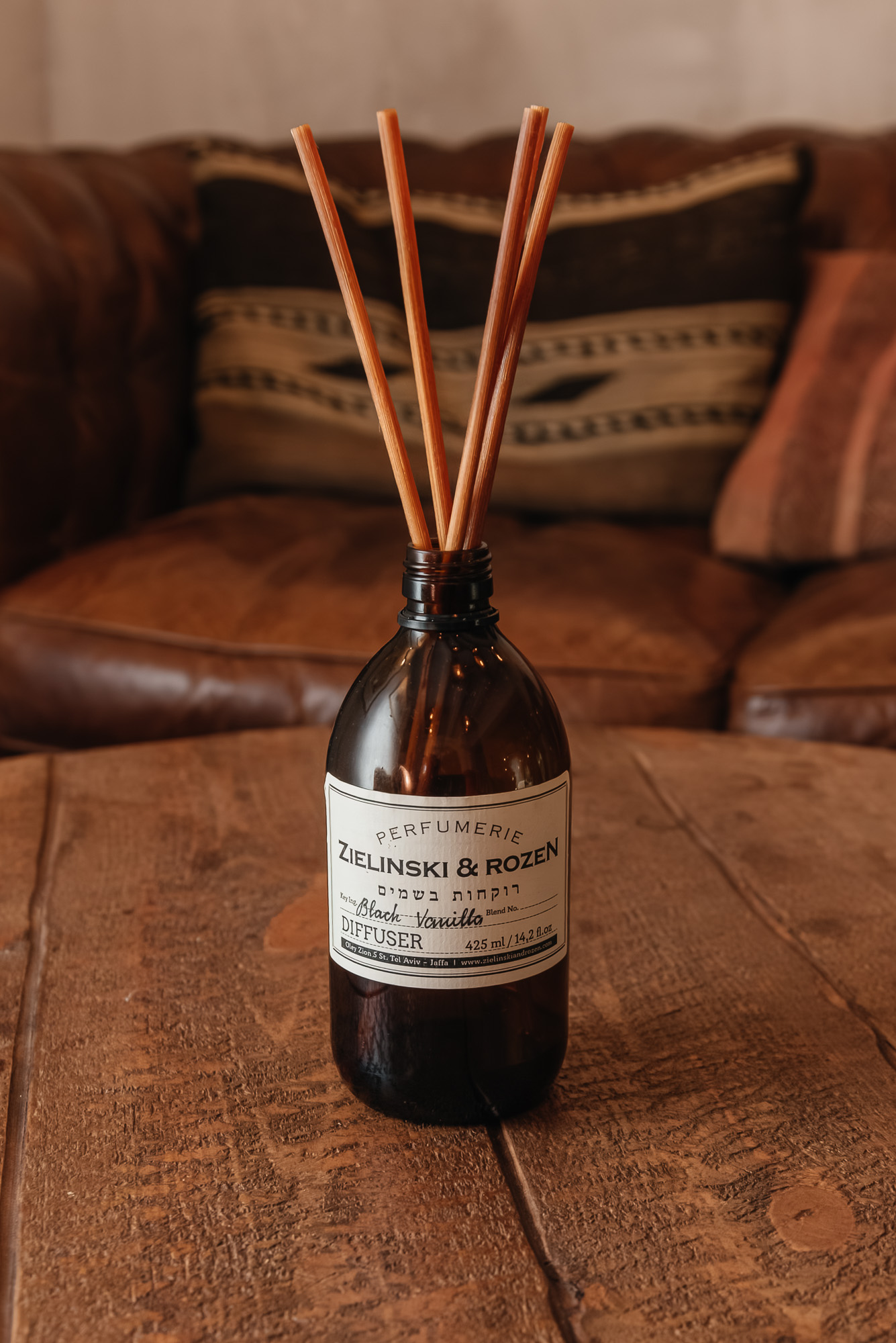 Difusor de aroma con varillas en un frasco ámbar sobre una mesa de madera.